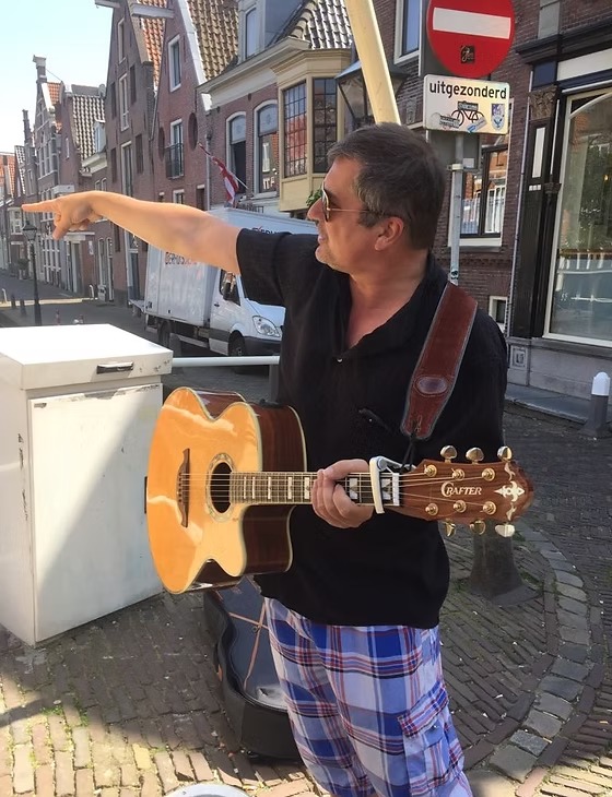 Sang pemandu-musisi memetik gitar di sebuah jalan kota Alkmaar