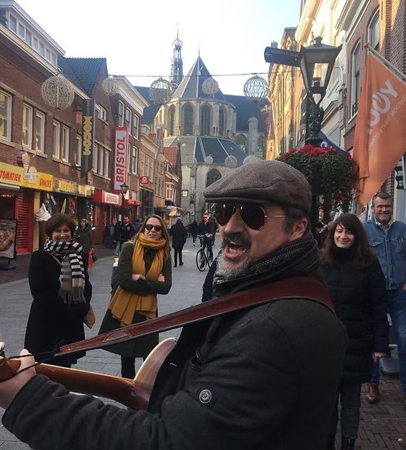 Sang pemandu di sebuah jalan ramai Alkmaar dengan menara gereja besar di kejauhan